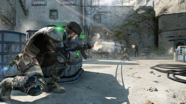 Splinter Cell Blacklist: Sam Fisher crouches behind wooden casks as he shoots at enemies.